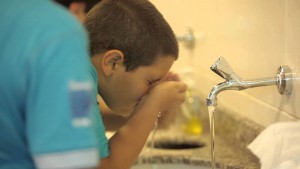 a child rinses his nose while performing ablution.